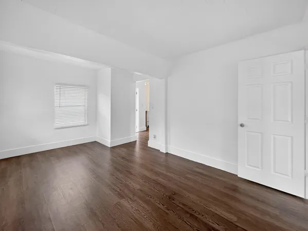 a view of an empty room with wooden floor and closet