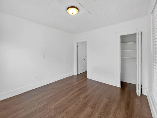 an empty room with wooden floor and window