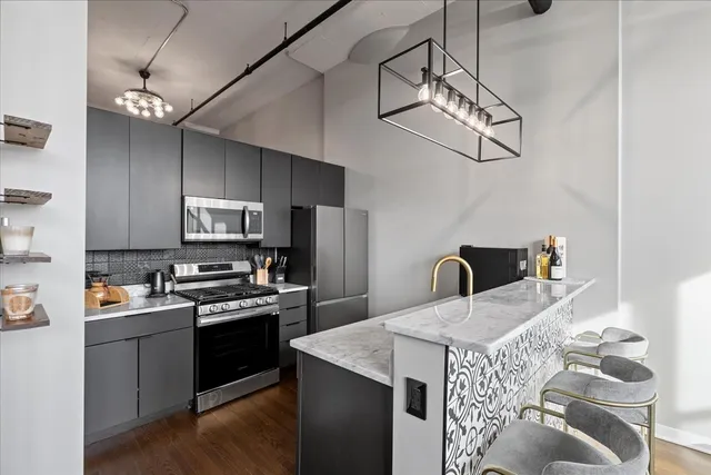 a kitchen with stainless steel appliances granite countertop a sink a stove a refrigerator cabinets a dining table and chairs