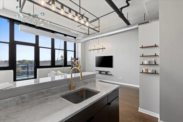 a kitchen with a sink a counter and a flat screen tv
