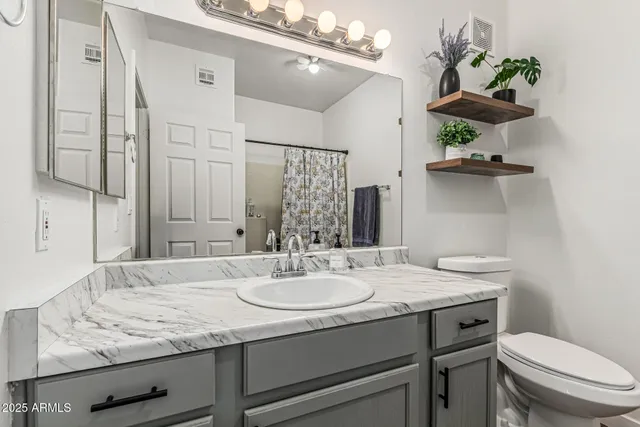 a bathroom with a granite countertop sink a toilet and a mirror