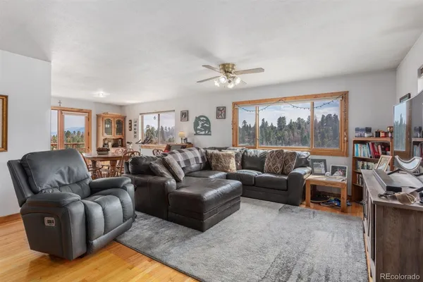 a living room with furniture ceiling fan and a wooden floor