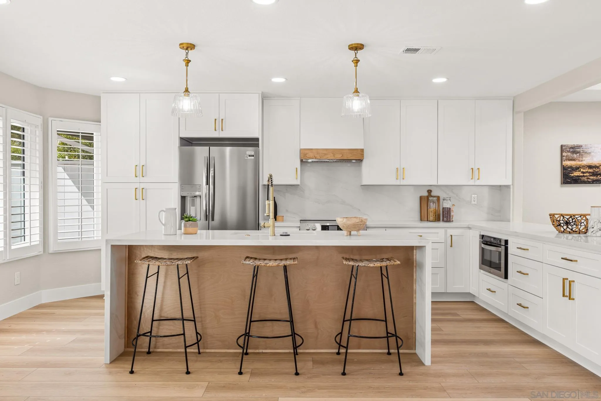 a kitchen with stainless steel appliances granite countertop a stove a sink a refrigerator and white cabinets with wooden floor