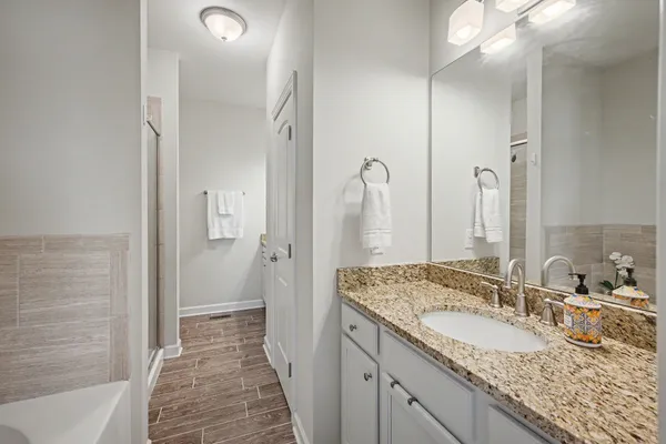 a bathroom with a granite countertop double vanity sink and mirror