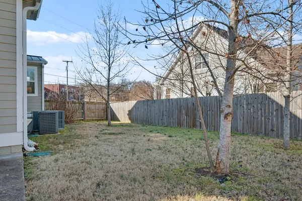 a view of a backyard with large trees and wooden fence