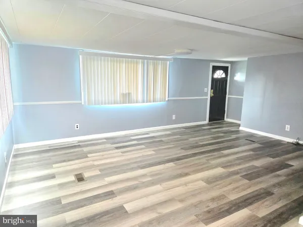 a view of a livingroom with an empty space & window