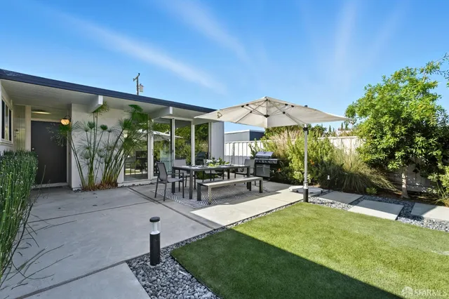 a view of a patio with a table and chairs under an umbrella