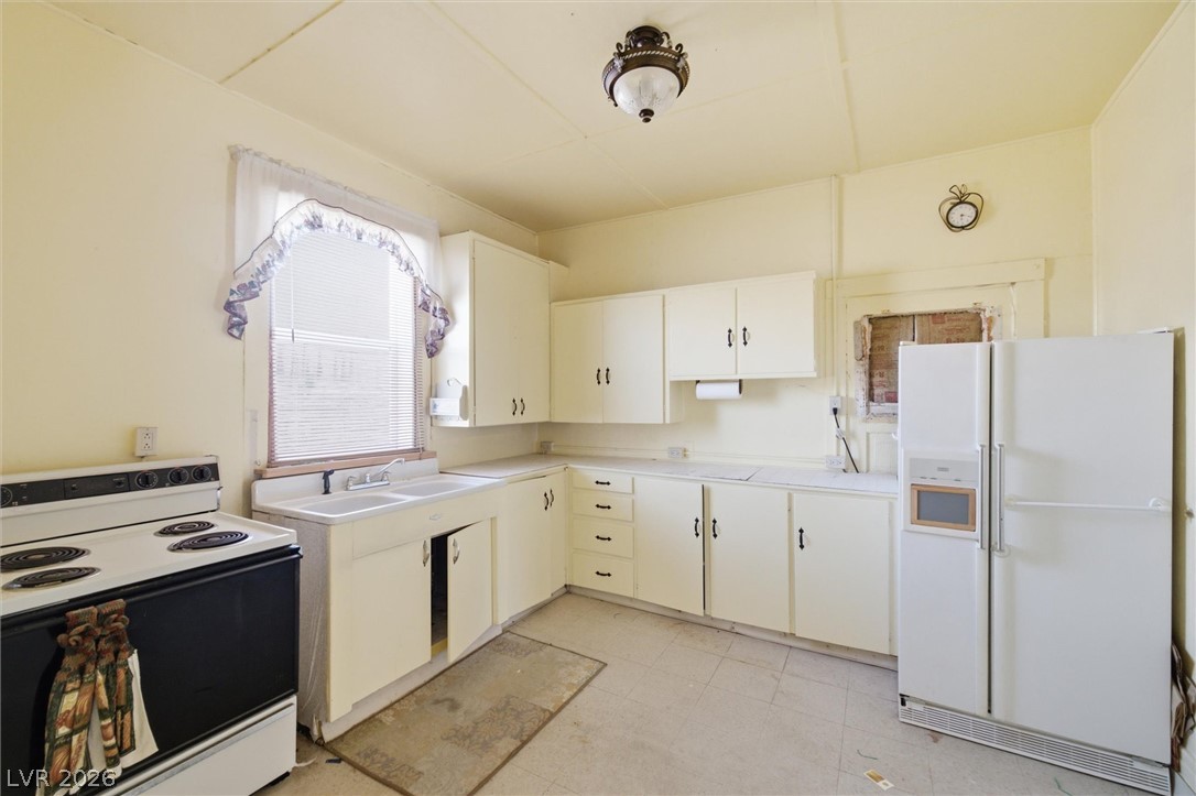 405 Main Street Beatty, NV 89003 - Photo 6 of 28 A well-lit kitchen featuring ample cabinetry, a double sink, and space for a large refrigerator.