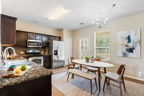 a kitchen with a dining table chairs and refrigerator