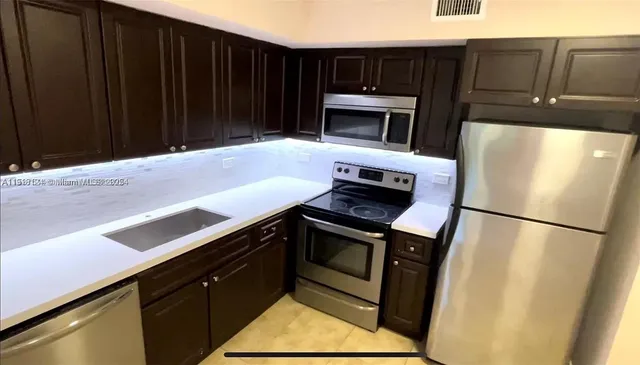 a kitchen with granite countertop a refrigerator stove and microwave
