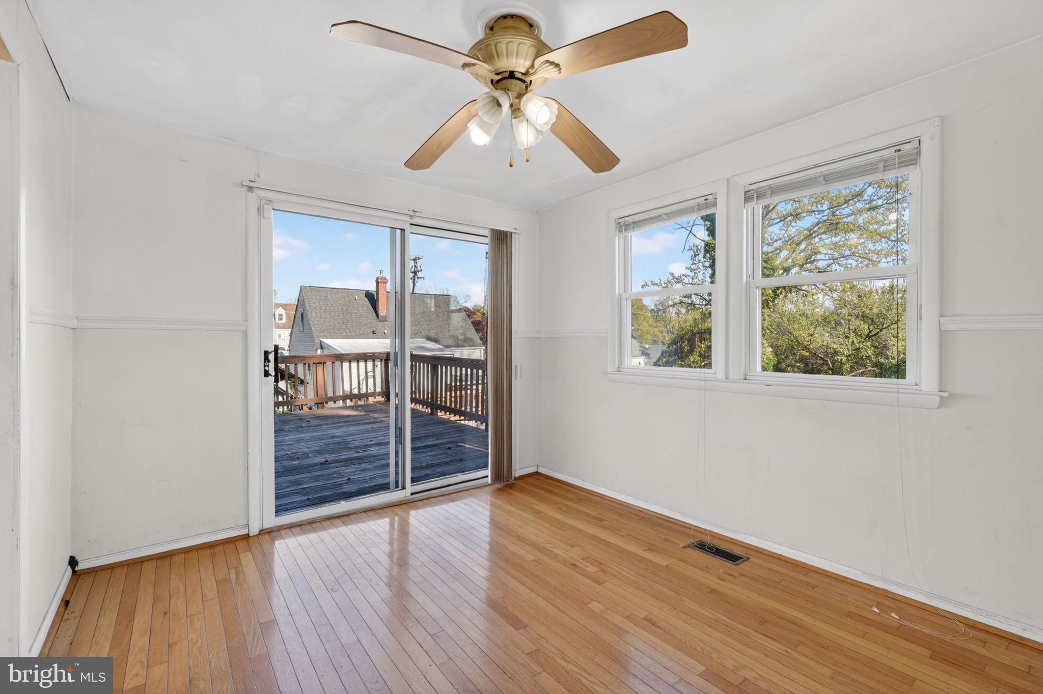 5441 Taussig Road Bladensburg, MD 20710 - Photo 2 of 37 an empty room with wooden floor chandelier fan and windows
