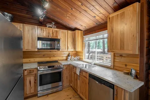 a kitchen with stainless steel appliances granite countertop a refrigerator a stove and a sink with large window