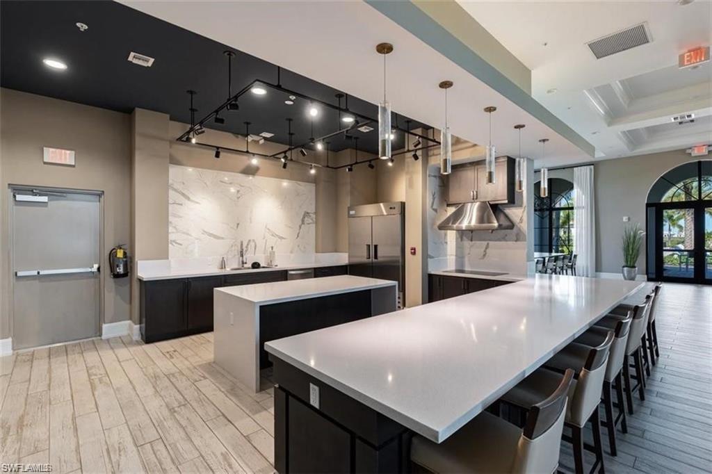 5265 Beckton Road Ave Maria, FL 34142 - Photo 30 of 35 Exhibition Kitchen featuring a kitchen breakfast bar, pendant lighting, stainless steel built in fridge, light stone countertops, and black electric stovetop
