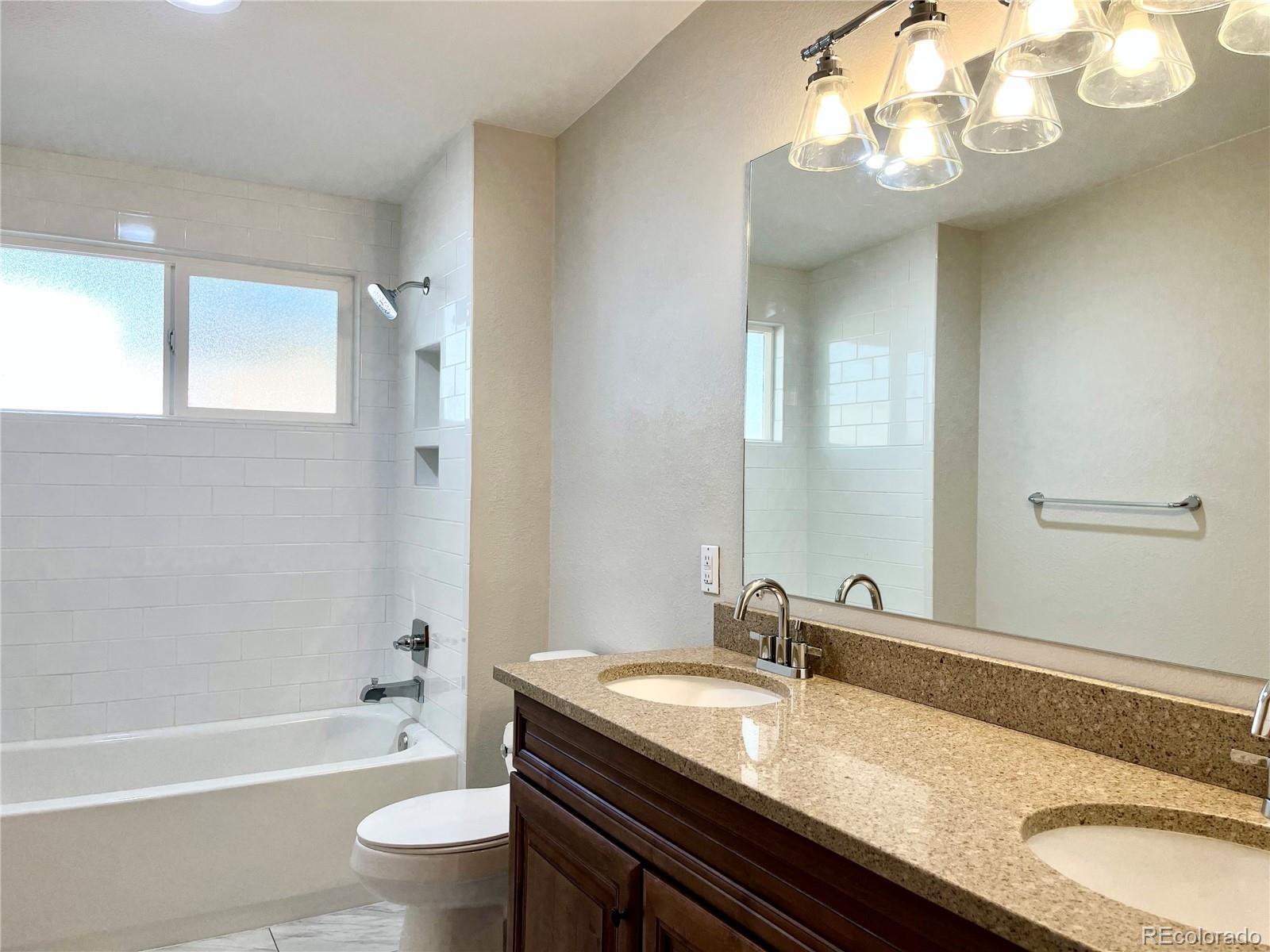 3907 Jasmine Street Colorado Springs, CO 80907 - Photo 17 of 23 a bathroom with a granite countertop sink a toilet and bathtub