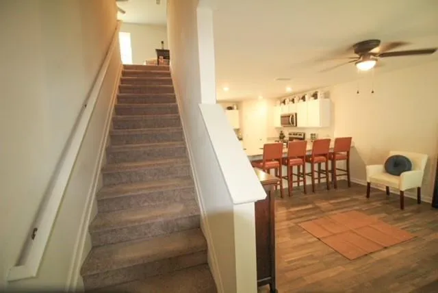 a living room with couches chairs and kitchen view with wooden floor