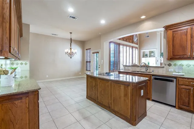 a large kitchen with kitchen island granite countertop a sink and dishwasher wooden cabinets with granite countertops