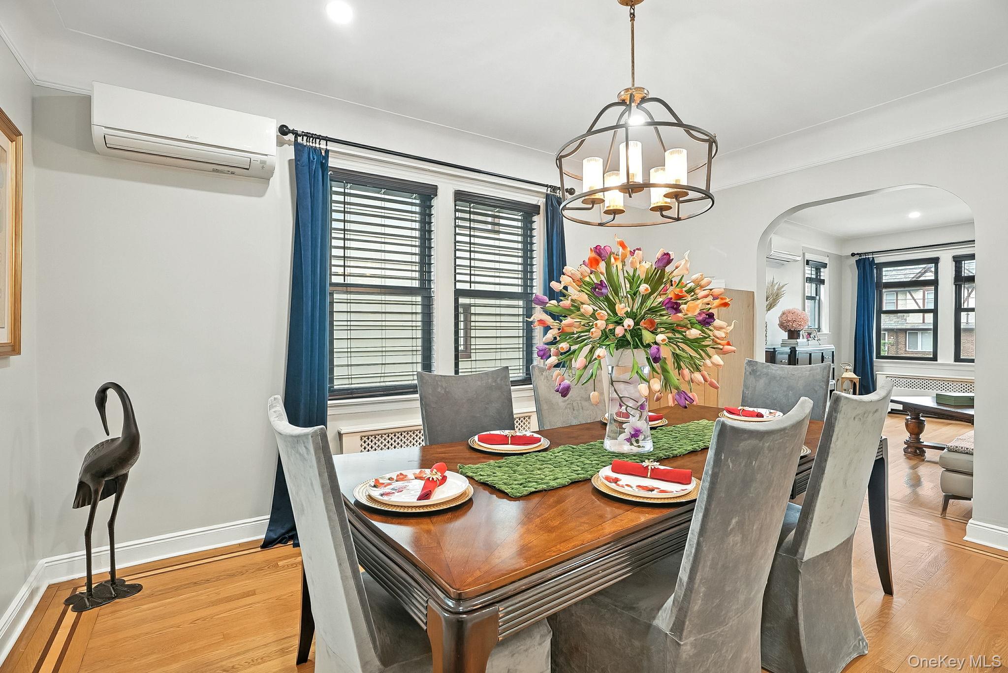 1260 Rhinelander Avenue Bronx, NY 10461 - Photo 14 of 50 Dining room with arched walkways, light wood-style floors, a wall mounted air conditioner, recessed lighting, and a chandelier