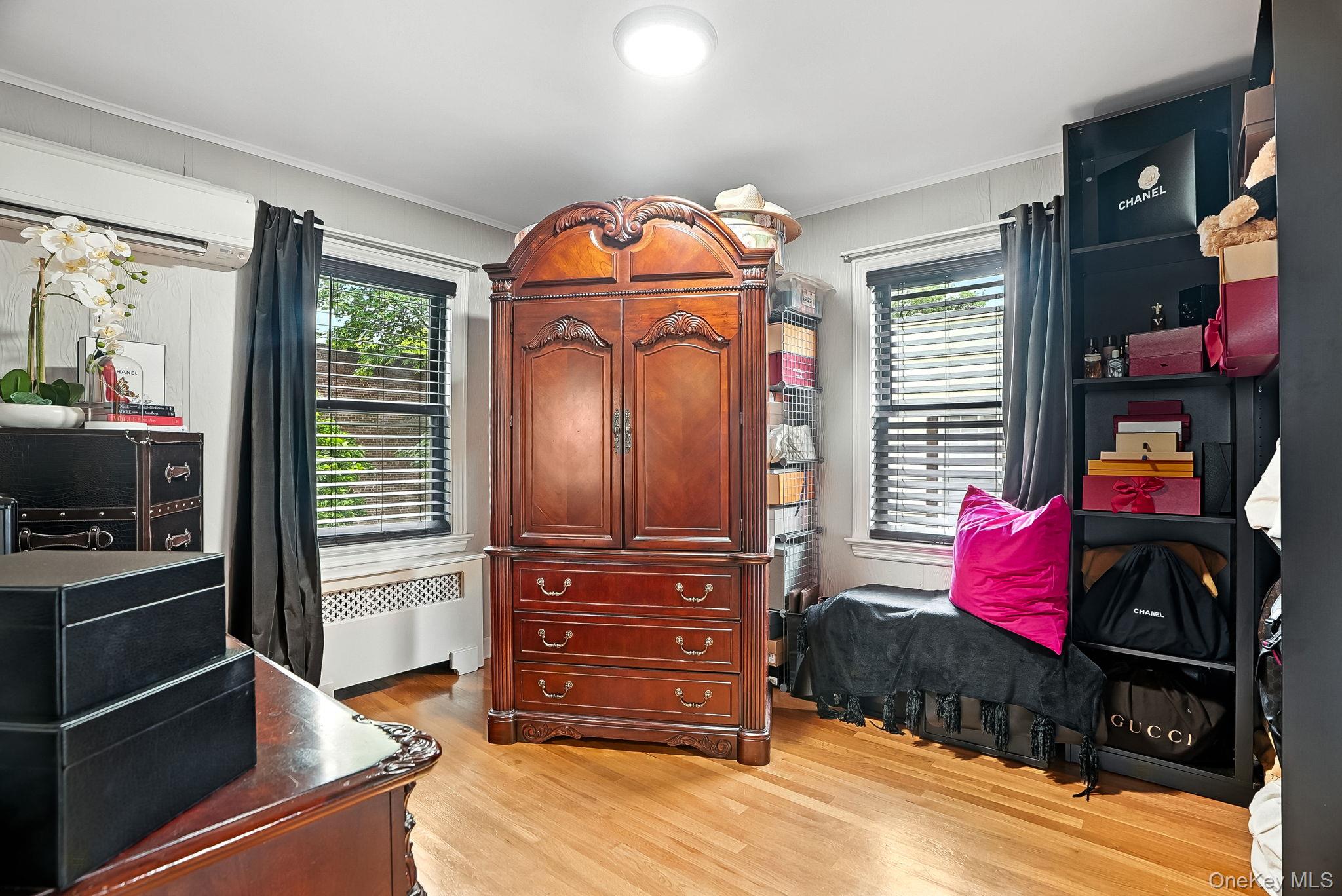 1260 Rhinelander Avenue Bronx, NY 10461 - Photo 21 of 50 Bedroom featuring light wood-style flooring, radiator heating unit, a wall unit AC, and crown molding