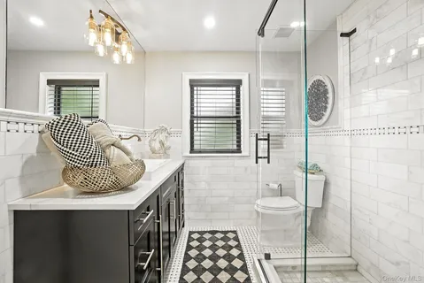 a bathroom with a granite countertop sink a toilet a mirror and shower