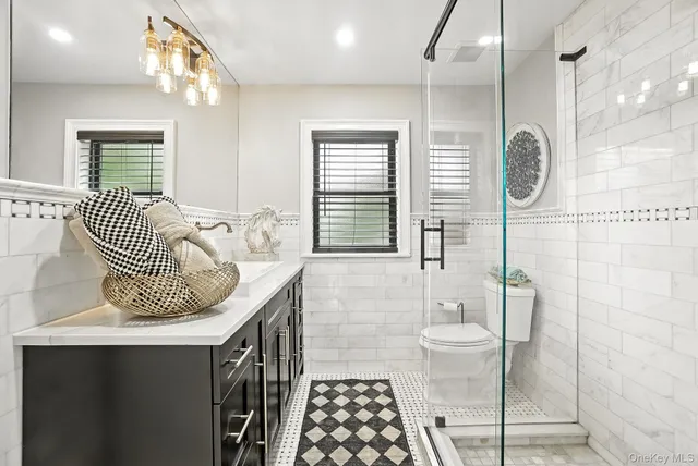 a bathroom with a granite countertop sink a toilet a mirror and shower