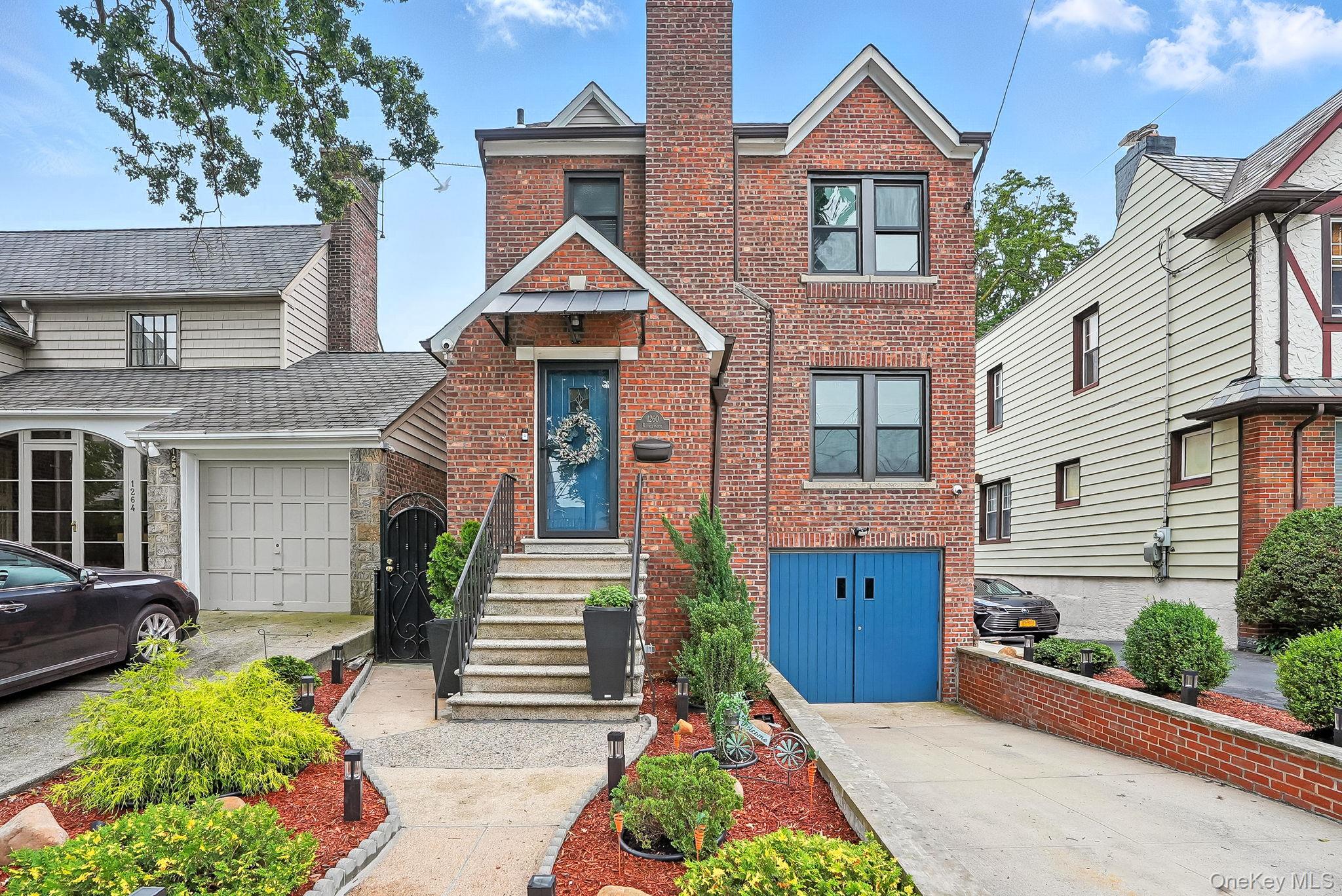 1260 Rhinelander Avenue Bronx, NY 10461 - Photo 44 of 50 View of front facade featuring brick siding, driveway, a garage, and a chimney