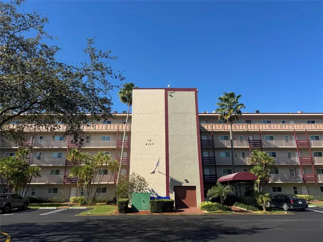 a front view of multi story residential apartment building with yard and traffic signal