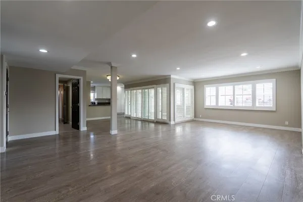 a view of an empty room with a window and wooden floor