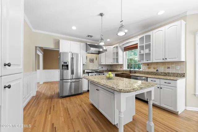 a kitchen with a center island wooden floor and stainless steel appliances