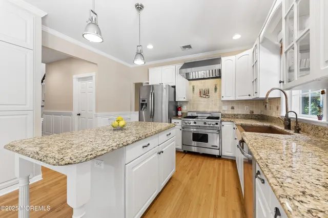 a kitchen with stainless steel appliances granite countertop a stove top oven a sink dishwasher and a refrigerator