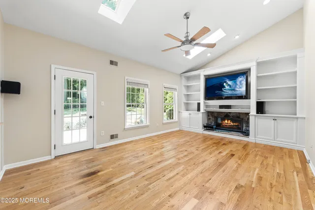 a view of empty room with fireplace and wooden floor