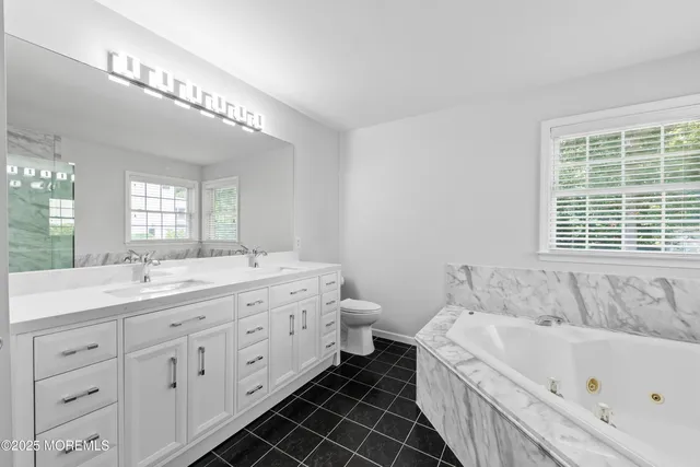 a bathroom with a double vanity sink a large mirror and a bathtub