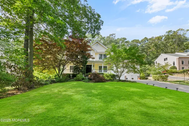 a view of a house with a big yard and large trees