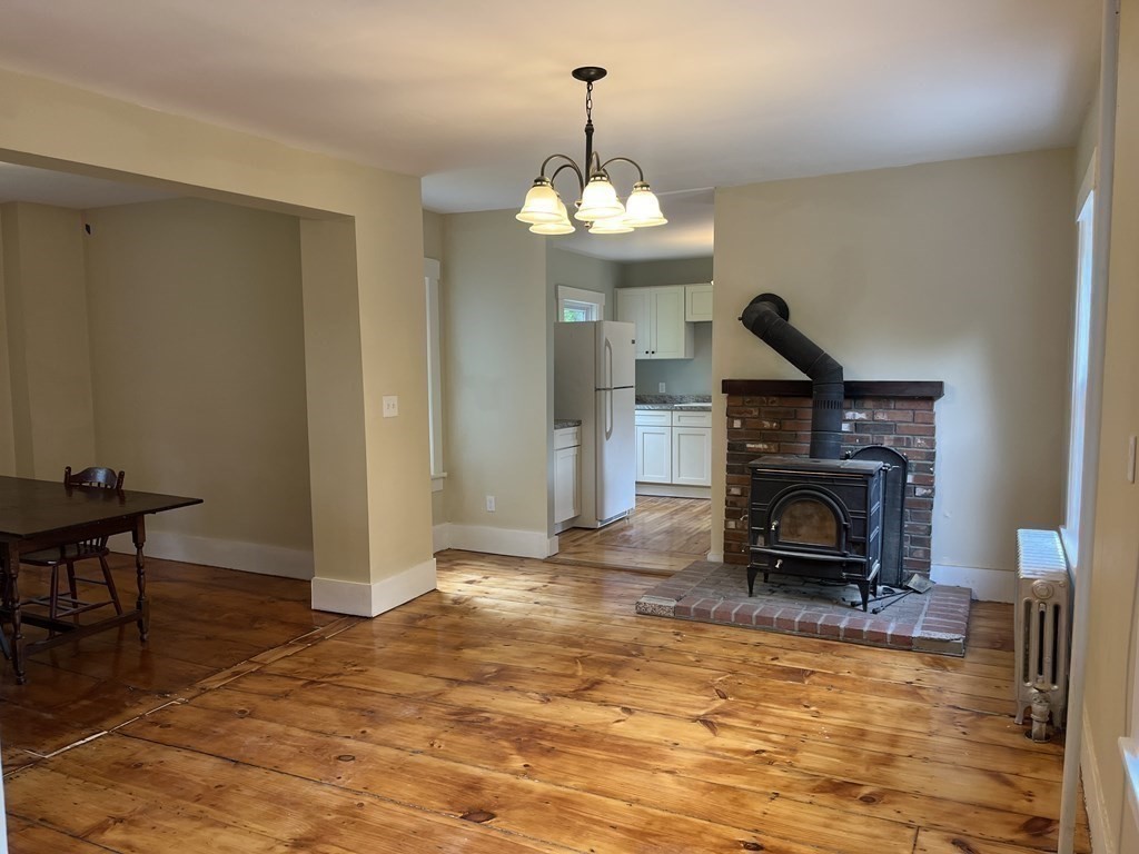 634 Patriots Road Templeton, MA 01468 - Photo 12 of 26 a view of a livingroom with a fireplace a chandelier and wooden floor