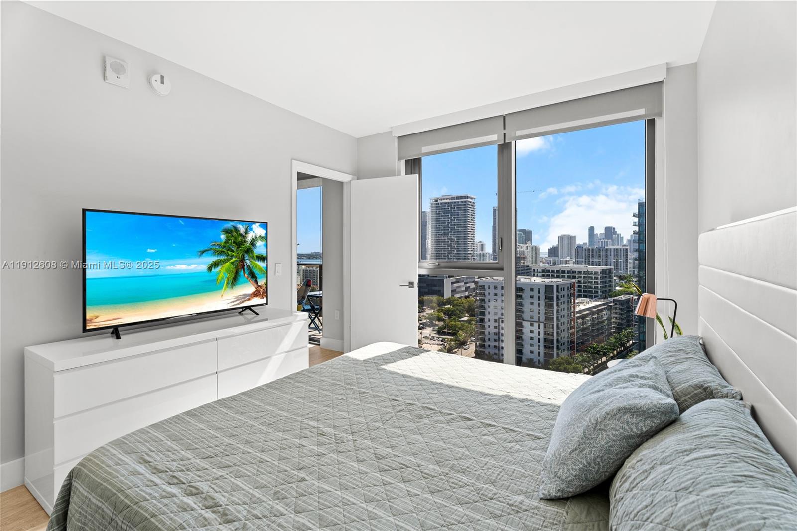 121 Northeast 34th Street, Unit 2003 Miami, FL 33137 - Photo 5 of 27 a bedroom with a bed and a flat tv screen next to a window