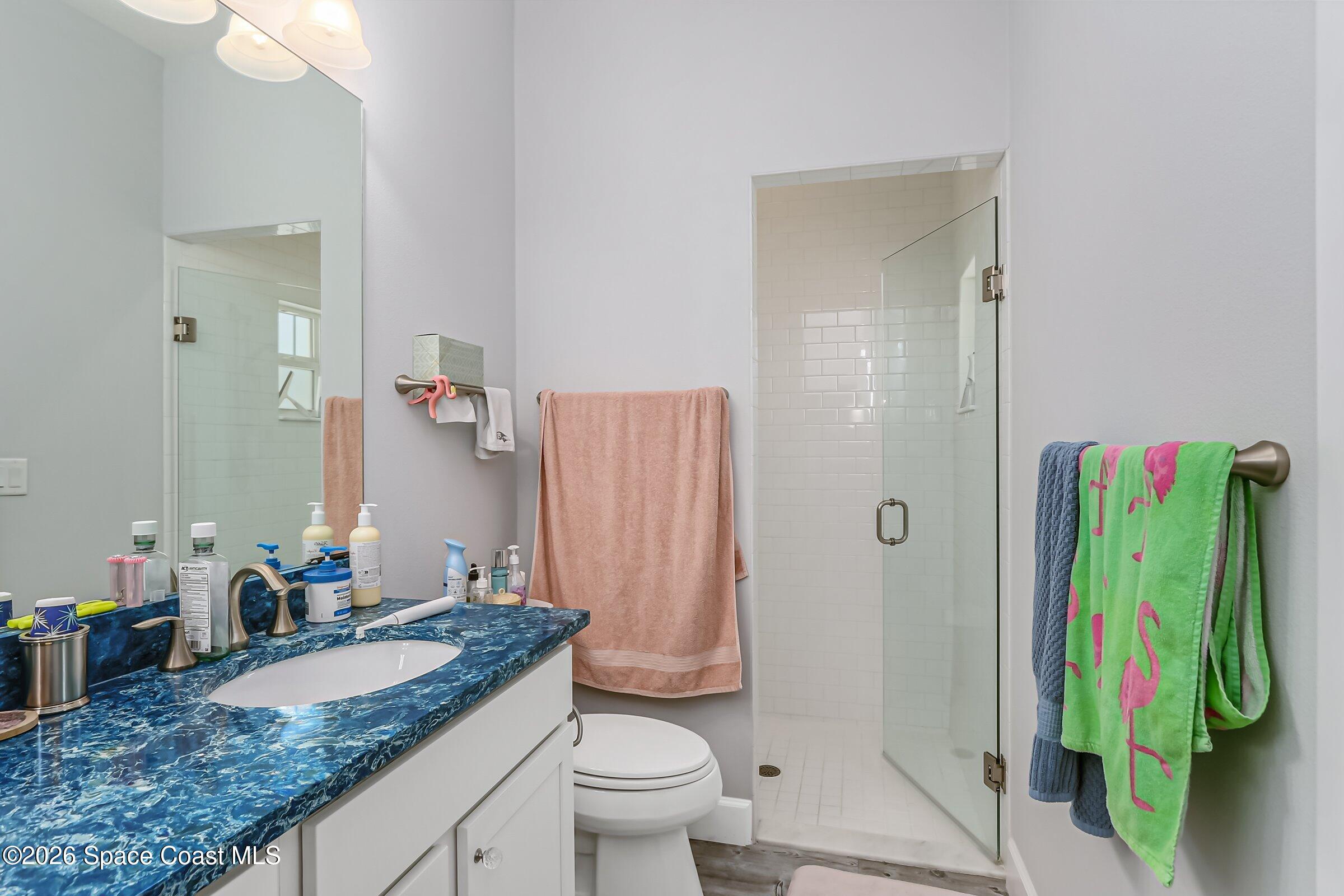 1399 Tullagee Avenue Melbourne, FL 32940 - Photo 20 of 53 a bathroom with a granite countertop sink a toilet and a shower