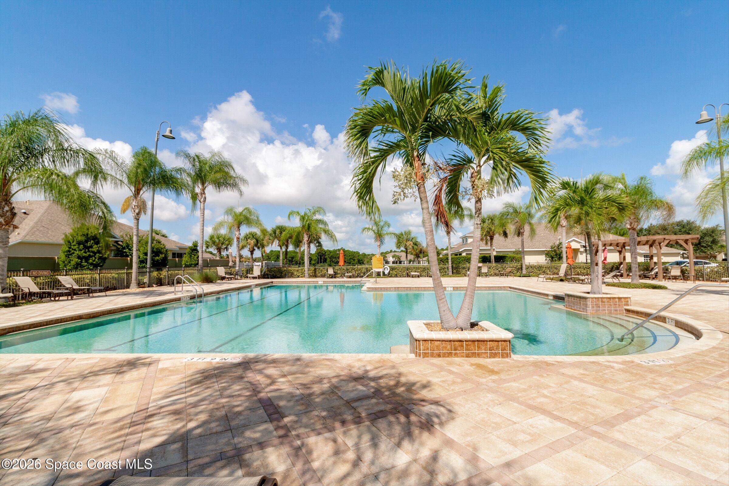1399 Tullagee Avenue Melbourne, FL 32940 - Photo 40 of 53 a view of a swimming pool with a lawn chairs and palm tree