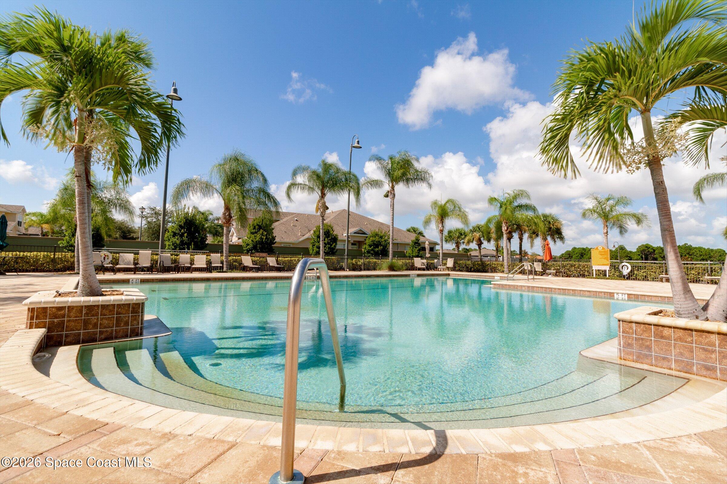 1399 Tullagee Avenue Melbourne, FL 32940 - Photo 42 of 53 a view of a swimming pool with a lawn chairs under palm trees