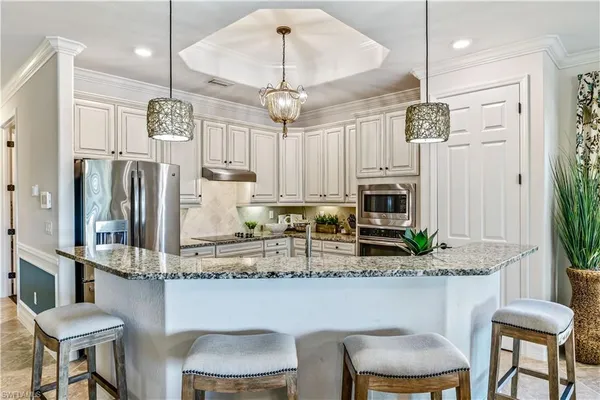a kitchen with stainless steel appliances granite countertop a table chairs refrigerator and microwave