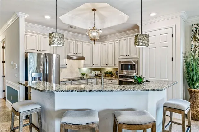 a kitchen with stainless steel appliances granite countertop a table chairs refrigerator and microwave