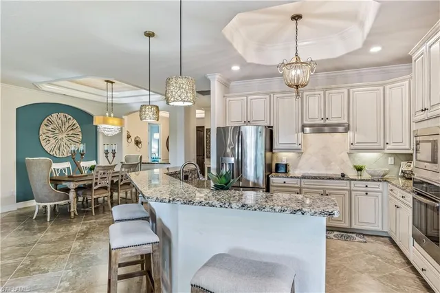 a kitchen with stainless steel appliances granite countertop a stove a sink a refrigerator a dining table and chairs