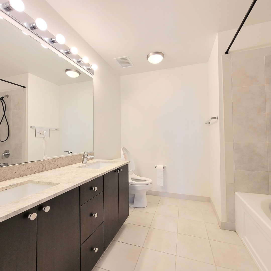 Undisclosed Address Chicago, IL 60607 - Photo 11 of 26 a spacious bathroom with a double vanity sink a toilet and a mirror