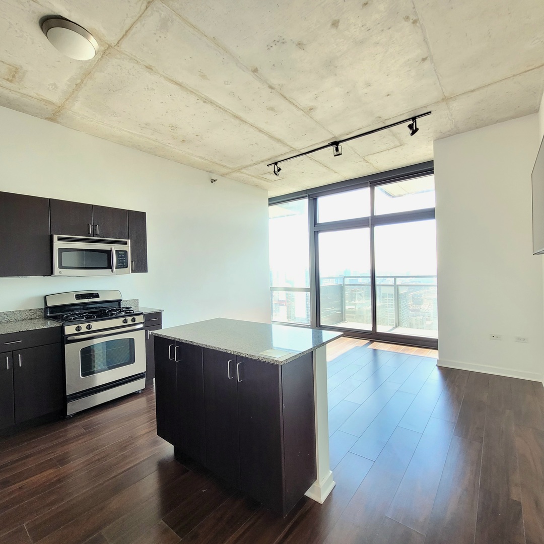 Undisclosed Address Chicago, IL 60607 - Photo 7 of 26 a open kitchen with granite countertop a stove top oven a sink and dishwasher with wooden floor
