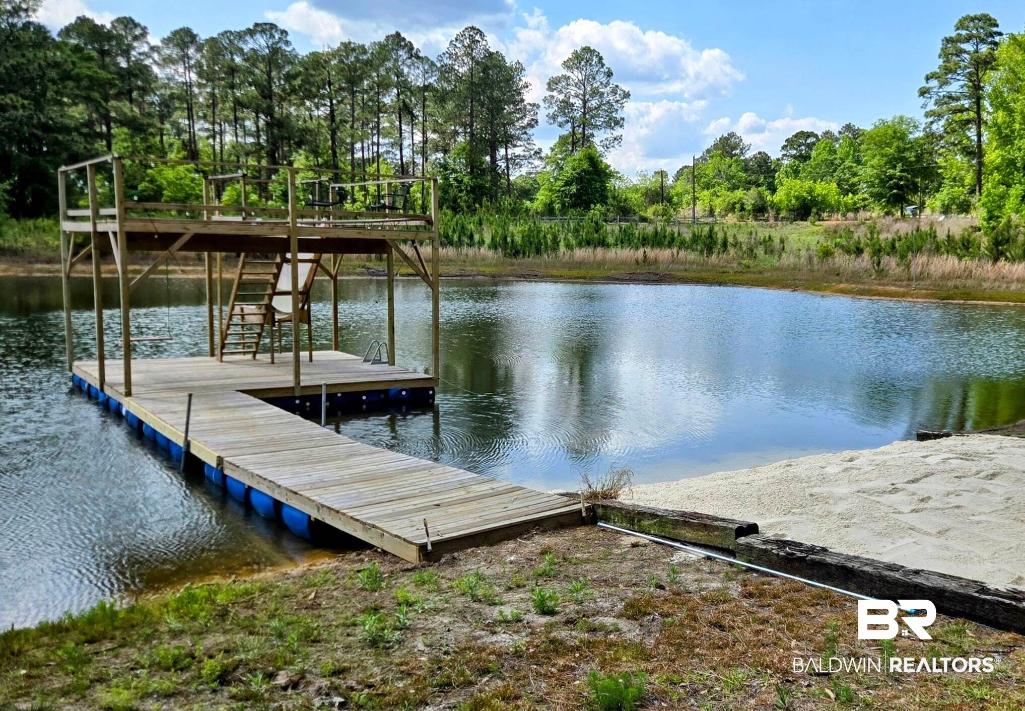3160 Old Castleberry Road Brewton, AL 36426 - Photo 33 of 36 Private pond with a multi-level wooden dock, sandy beach area, and surrounding natural landscaping