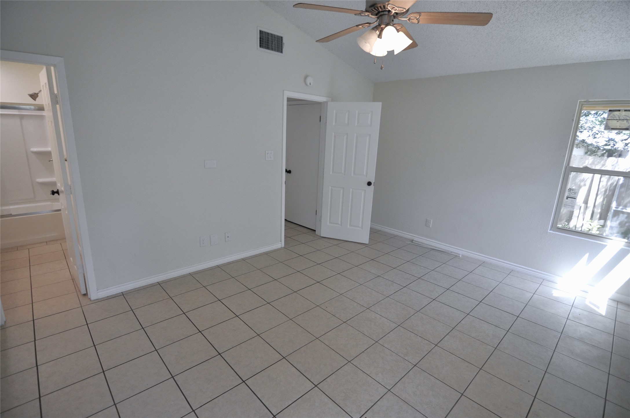 8809 Piney Point Drive, Unit B Austin, TX 78729 - Photo 9 of 10 A well-lit bedroom features vaulted ceilings and practical tile flooring.