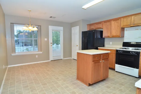 a kitchen with stainless steel appliances a stove top oven a refrigerator a sink and dishwasher with white cabinets