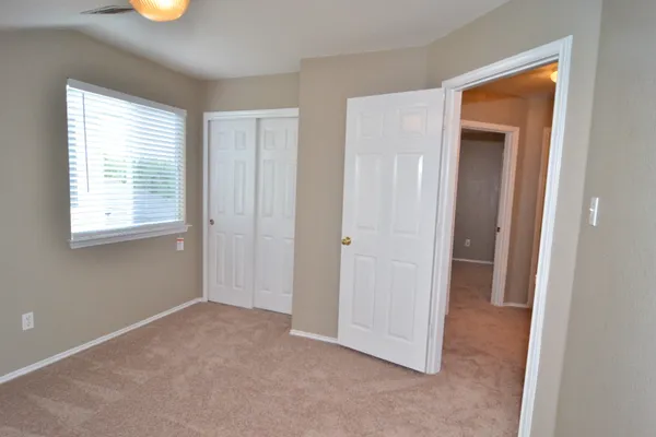 a view of an empty room with closet and a window