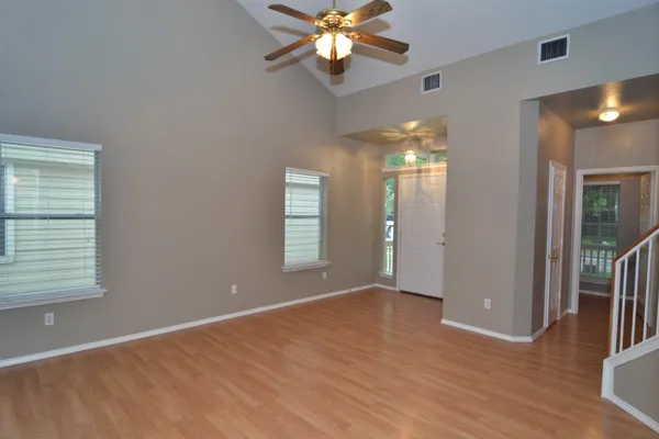 a view of an empty room with window and wooden floor