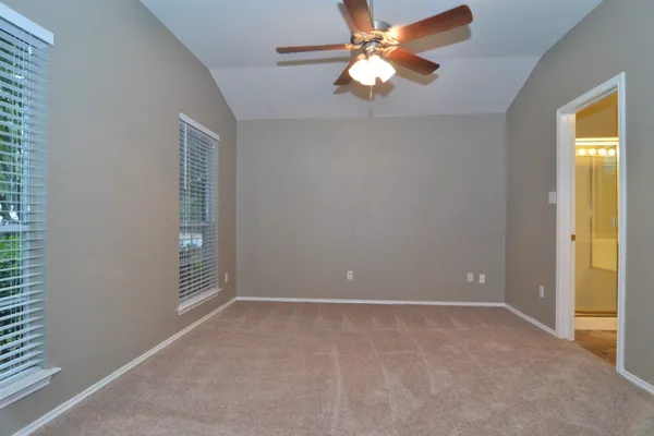 an empty room with windows and fan