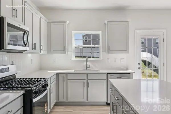 a kitchen with stainless steel appliances granite countertop a sink stove and cabinets