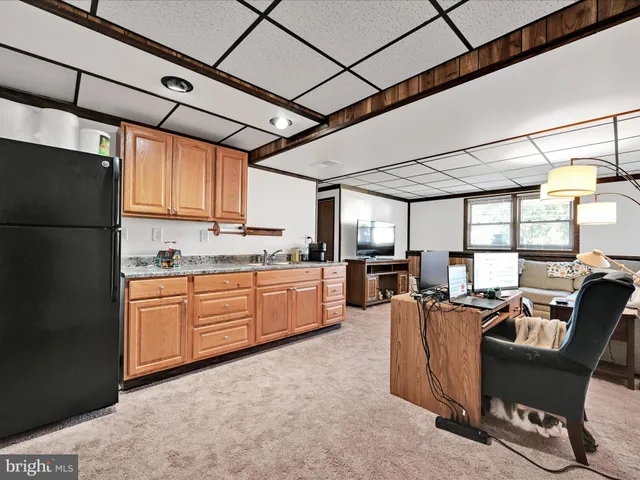 a kitchen with stainless steel appliances granite countertop a refrigerator a sink dishwasher a dining table and chairs with wooden floor